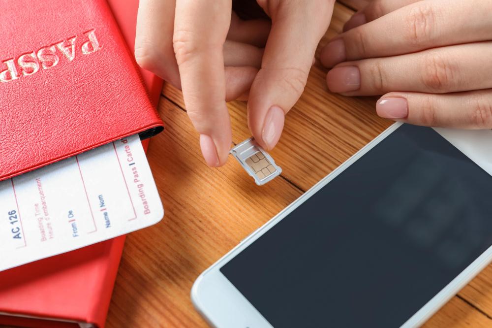 Travel SIM card being inserted into a smartphone next to a passport