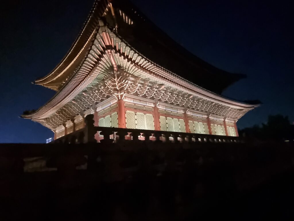 Gyeongbokgung Palace illuminated at night against a dark blue evening sky