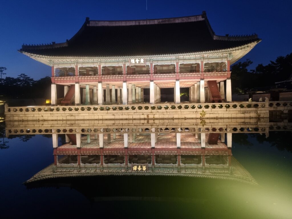 Gyeongbokgung Palace illuminated at night with its reflection in a pond