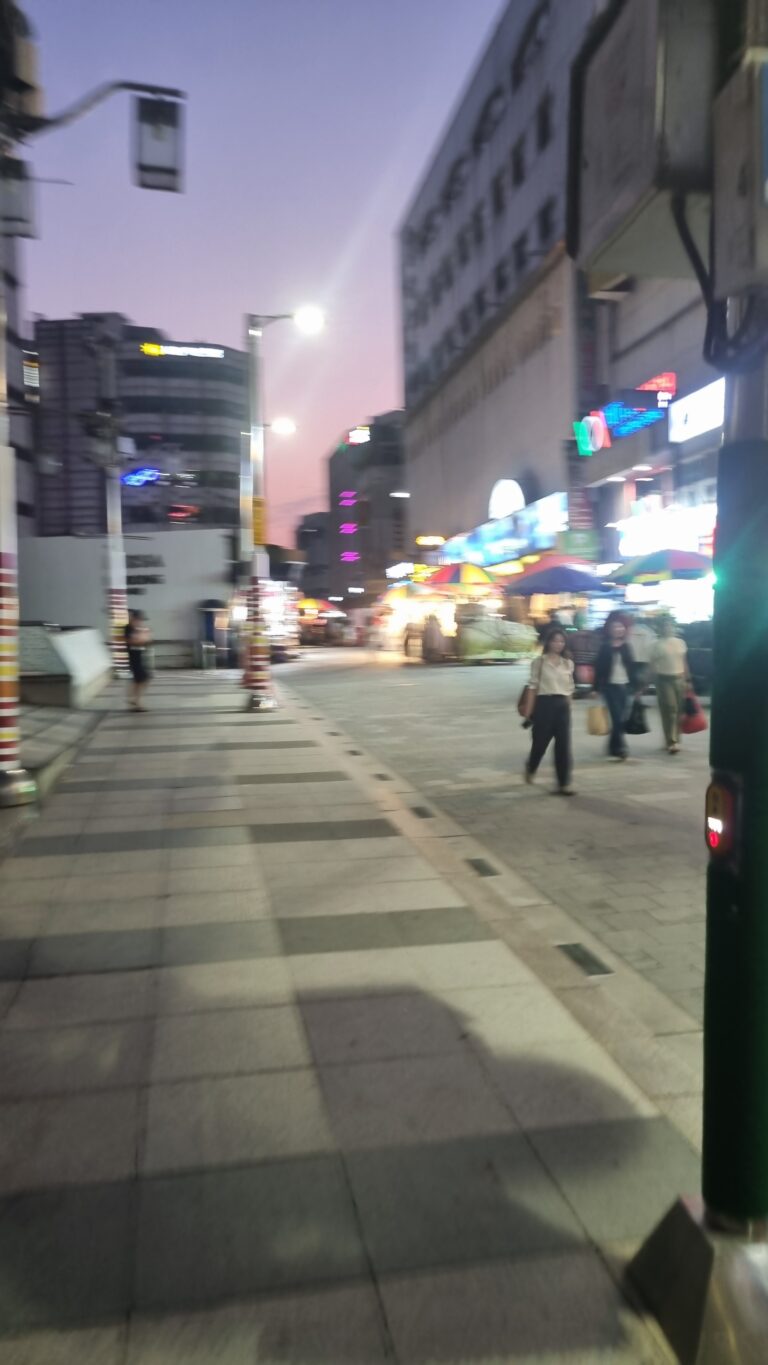 Namdaemun Market street at dusk with shops, food stalls, and pedestrians in Seoul