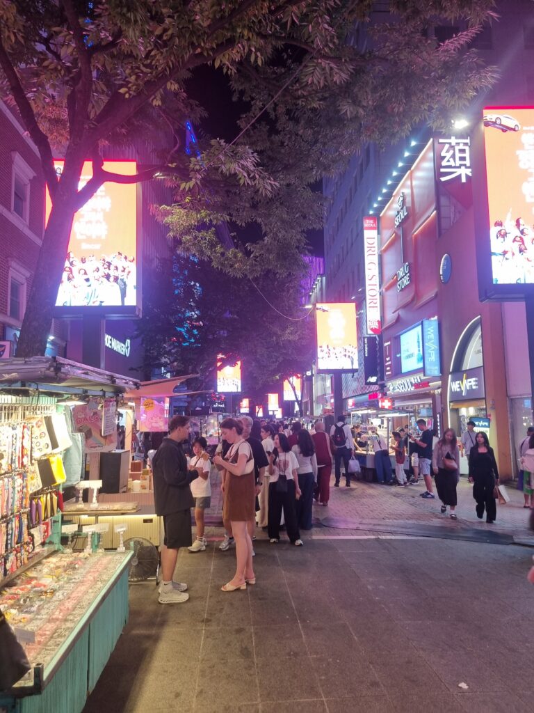 Busy Myeongdong shopping street at night with colorful signs and storefronts in Seoul