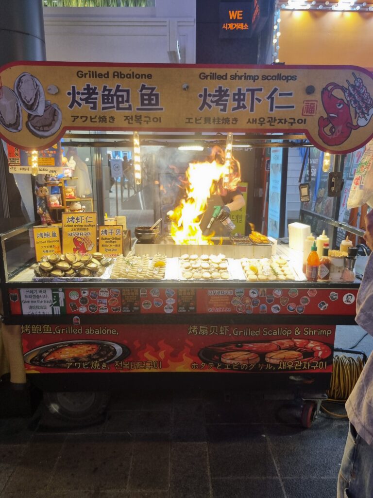 Grilled abalone, scallops, and shrimp at a Myeongdong street food stall in Seoul
