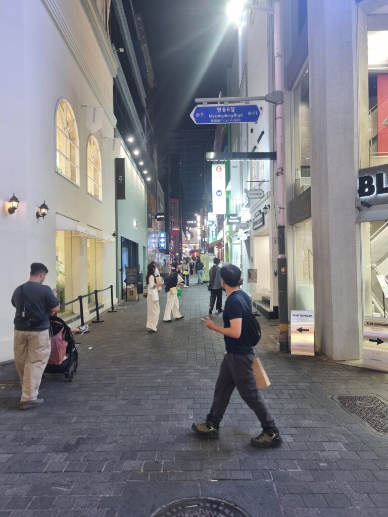 Myeongdong shopping alley at night with pedestrians, shops, and illuminated signs
