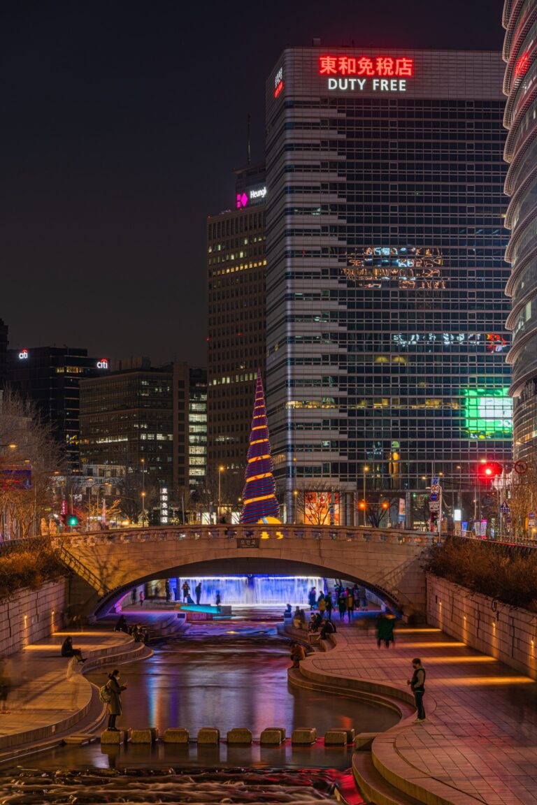 Night view of Cheonggyecheon Stream near Cheonggye Plaza featuring illuminated bridge, waterfall light, and downtown Seoul skyscrapers